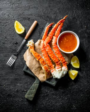 Soslu deniz yengeci ve dilimlenmiş limon. Siyah rustik arka plan üzerinde