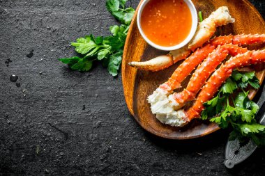 Maydanoz ve soslu bir tabakta taze yengeç. Siyah rustik arka plan üzerinde