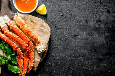 Soslu yengeç ve otlar. Siyah rustik arka plan üzerinde