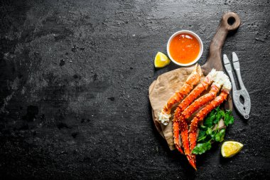 Limon dilimi, maydanoz ve soslu taze yengeç. Siyah rustik arka plan üzerinde