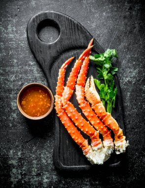 Yengeç bir kase içinde yeşillik ve sos ile kesme Tahtası üzerinde. Koyu rustik arka plan üzerinde