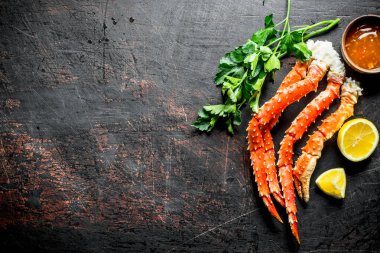 Otlar, sos ve dilimlenmiş limon ile Haşlanmış yengeç. Koyu rustik arka plan üzerinde