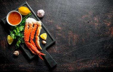 Limon dilimleri, maydanoz, sos ve sarımsak karanfil ile Yengeç. Koyu rustik arka plan üzerinde