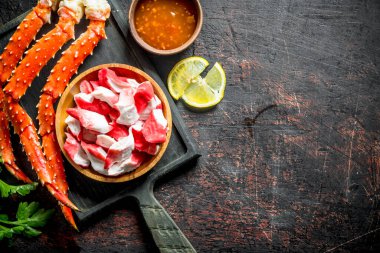 Yengeç eti ve taze yengeç, sos ve limon dilimleri. Koyu rustik arka plan üzerinde