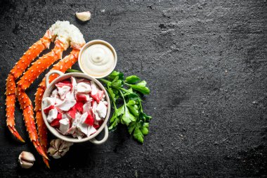 Soslu yengeç eti, otlar ve sarımsak karanfil. Siyah rustik arka plan üzerinde