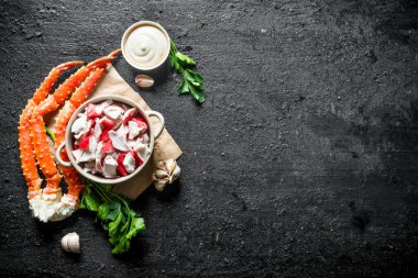 Soslu yengeç eti, otlar ve sarımsak karanfil. Siyah rustik arka plan üzerinde