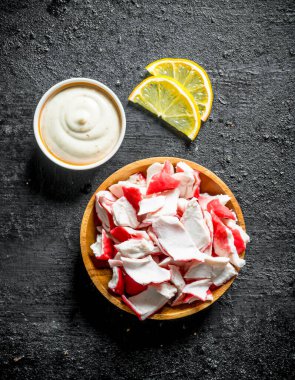 Sos lu ve limon dilimleri olan bir tabakta yengeç eti. Siyah rustik arka plan üzerinde