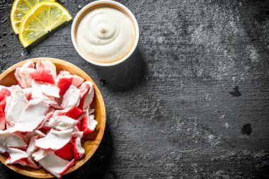 Sos lu ve limon dilimleri olan bir tabakta yengeç eti. Siyah rustik arka plan üzerinde