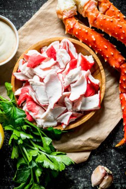 Maydanoz ve sos ile kağıt üzerinde bir tabakta yengeç eti. Koyu rustik arka plan üzerinde