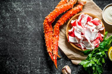 Maydanoz ve sos ile kağıt üzerinde bir tabakta yengeç eti. Koyu rustik arka plan üzerinde