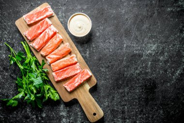 Yengeç yeşillik ve sos ile ahşap kesme Tahtası üzerinde sopalarla. Koyu rustik arka plan üzerinde