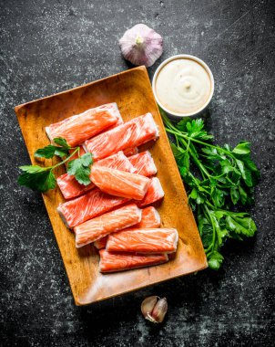 Yengeç sarımsak, otlar ve sos ile sopalarla. Koyu rustik arka plan üzerinde