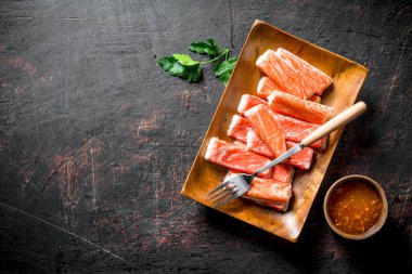 Yengeç çatal ve soslu bir tabağa yapışır. Koyu rustik arka plan üzerinde