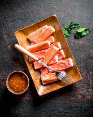 Yengeç çatal ve soslu bir tabağa yapışır. Koyu rustik arka plan üzerinde