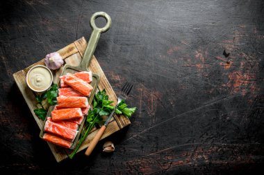 Yengeç otlar, sarımsak ve sos ile ahşap tepsiye sopalarla. Koyu rustik arka plan üzerinde