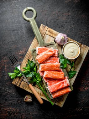 Yengeç otlar, sarımsak ve sos ile ahşap tepsiye sopalarla. Koyu rustik arka plan üzerinde