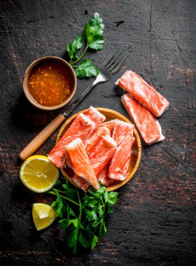 Yengeç limon dilimleri, otlar ve sos ile sopalarla. Koyu rustik arka plan üzerinde