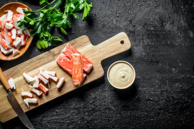 Dilimlenmiş yengeç sos ve otlar ile sopalarla. Siyah rustik arka plan üzerinde