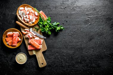 Dilimlenmiş yengeç sos ve maydanoz ile sopa. Siyah rustik arka plan üzerinde