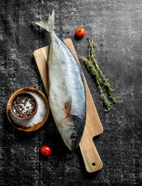 Kekik ve baharatlar ile kesme Tahtası üzerinde çiğ ton balığı. Koyu rustik arka plan üzerinde