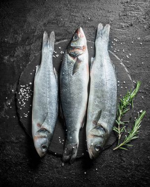 Siyah taş tahtaüzerinde biberiyeli çiğ balık. Siyah rustik arka plan üzerinde
