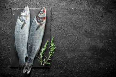 Biberiyeli bir taş tahtada taze çiğ balık. Siyah rustik arka plan üzerinde