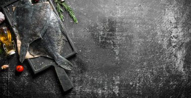 Biberiye ile kağıt üzerinde taze ham pisi balığı. Koyu rustik arka plan üzerinde