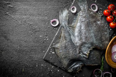 Domates ve soğan halkaları ile balık çiğ pisi balığı. Siyah rustik arka plan üzerinde