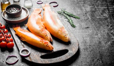 Baharat, domates ve soğan halkaları ile çiğ balık alabalık. Koyu rustik arka plan üzerinde