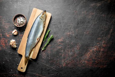 Sarımsak, baharat ve biberiye ile bir kesme Tahtası üzerinde tuzlu ringa balığı. Koyu rustik arka plan üzerinde