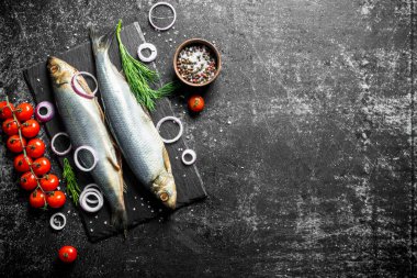 Domates, soğan ve otlar ile tuzlu ringa balığı. Koyu rustik arka plan üzerinde