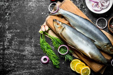 Limon, dereotu ve soğan ile tuzlu ringa balığı. Koyu rustik arka plan üzerinde