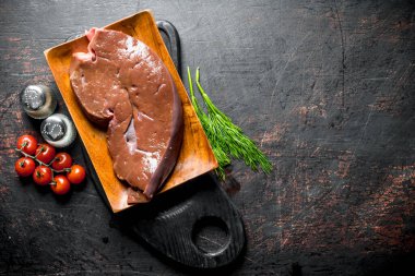 Kesme Kurulu otlar, domates ve baharatlar ile Çiğ karaciğer. Koyu rustik arka plan üzerinde