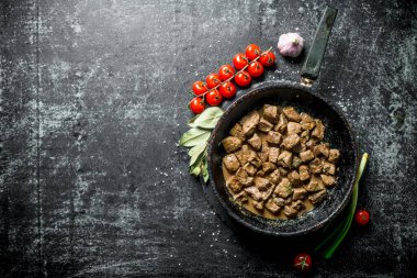 Sarımsak, kiraz domates ve Defne yaprağı ile karaciğer kızarmış parçalar. Koyu rustik arka plan üzerinde