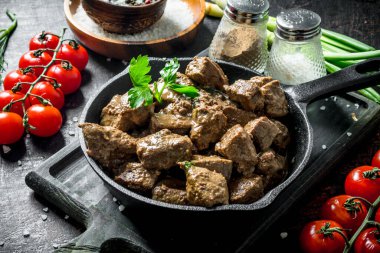 Bir kesme Tahtası üzerinde baharat ve kiraz domates ile kızarmış karaciğer. Koyu rustik arka plan üzerinde