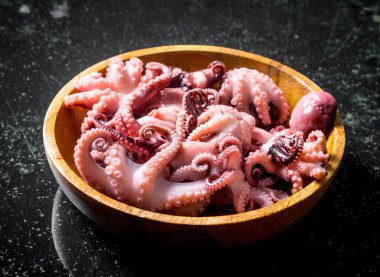 Tahta bir tabakta bebek ahtapot. Koyu rustik arka plan üzerinde