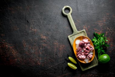 Kireç ve yeşillikli kesme tahtasında bebek ahtapot. Koyu rustik arka plan üzerinde