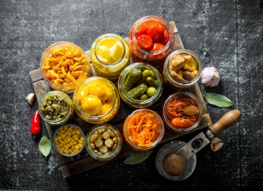 Tepside çeşitli korunmuş gıda kavanoz. Koyu rustik arka plan üzerinde