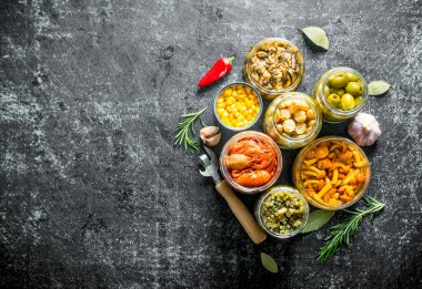 Biberiye ve sarımsak kavanozlarda salamura gıda. Koyu rustik arka plan üzerinde