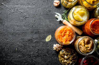 Salamura yiyecek kavanozları. Siyah rustik arka plan üzerinde