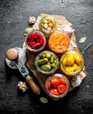 Kağıt üzerinde konserve sebze kavanozları. Siyah rustik arka plan üzerinde