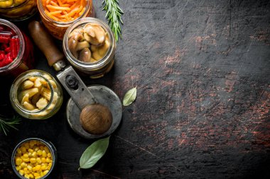 Kavanozlarda çeşitli korunmuş sebzeler. Koyu rustik arka plan üzerinde