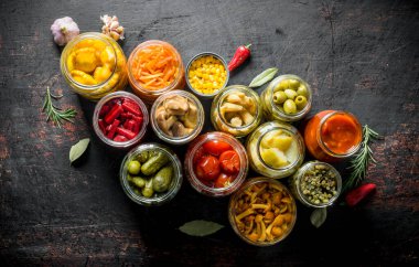 Kavanozlarda çeşitli korunmuş sebzeler. Koyu rustik arka plan üzerinde