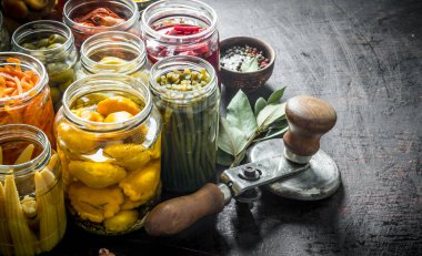 Bay yaprağı ile kavanozlarda çeşitli korunmuş gıda. Koyu rustik arka plan üzerinde