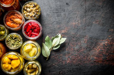 Bay yaprağı ile kavanozlarda çeşitli korunmuş gıda. Koyu rustik arka plan üzerinde