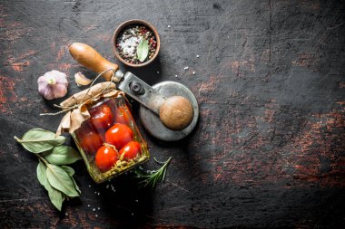 Defne yaprağı ve sarımsak karanfil ile korunmuş domates. Koyu rustik arka plan üzerinde