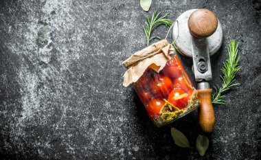 Biberiye ile cam bir kavanozda domates turşusu. Koyu rustik arka plan üzerinde