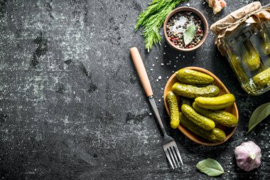 Çatallı bir tabakta korunmuş ev yapımı salatalıklar. Koyu rustik arka plan üzerinde