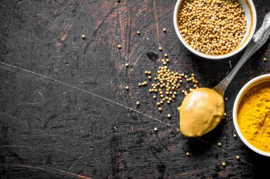 Bir kase ve kaşıkta hardal. Koyu rustik arka plan üzerinde