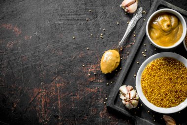 Kesme Tahtası'nda farklı türde hardallar var. Koyu rustik arka plan üzerinde